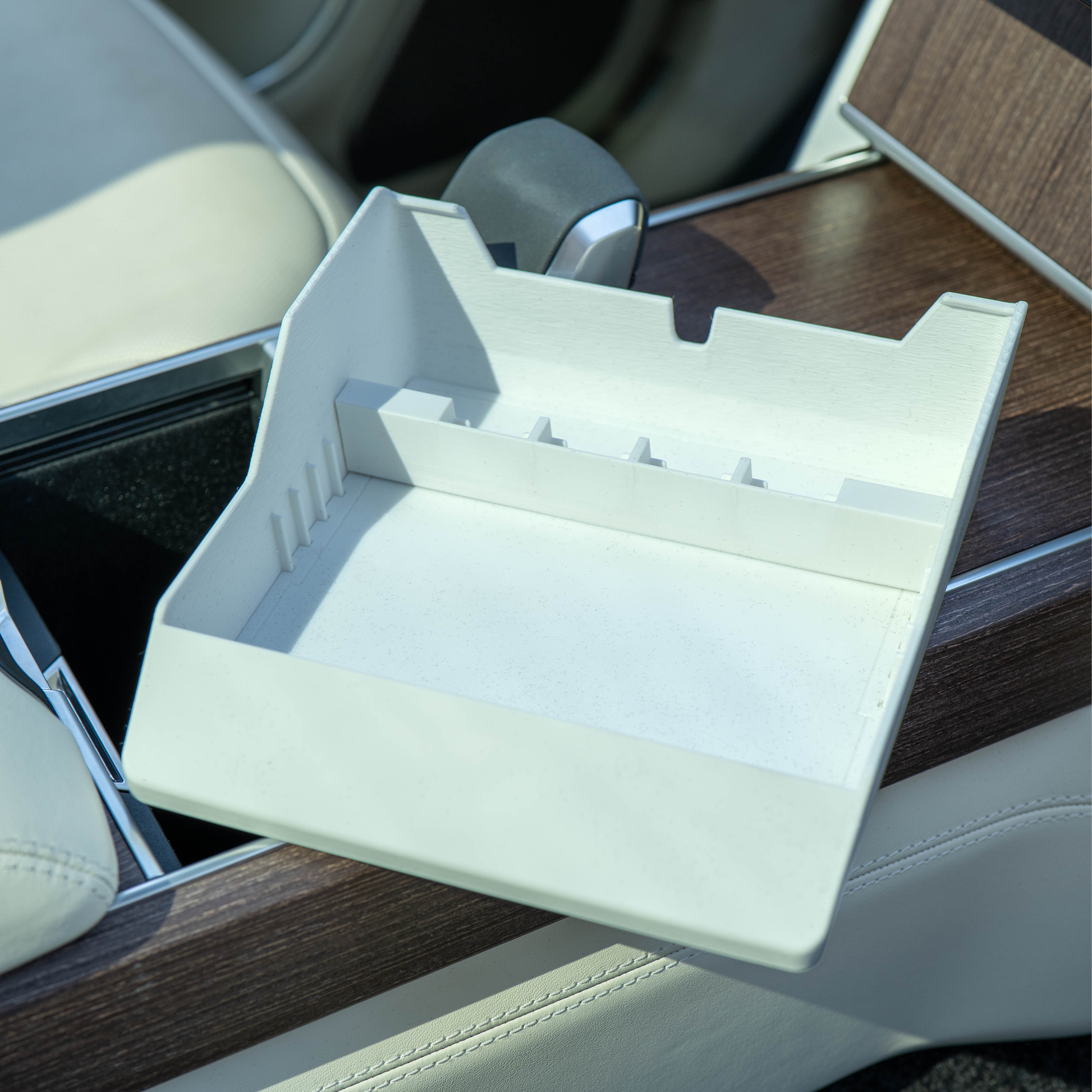 Empty white Range Rover Hidden Storage Organizer tray angled on the center console, showing divider and coin slots