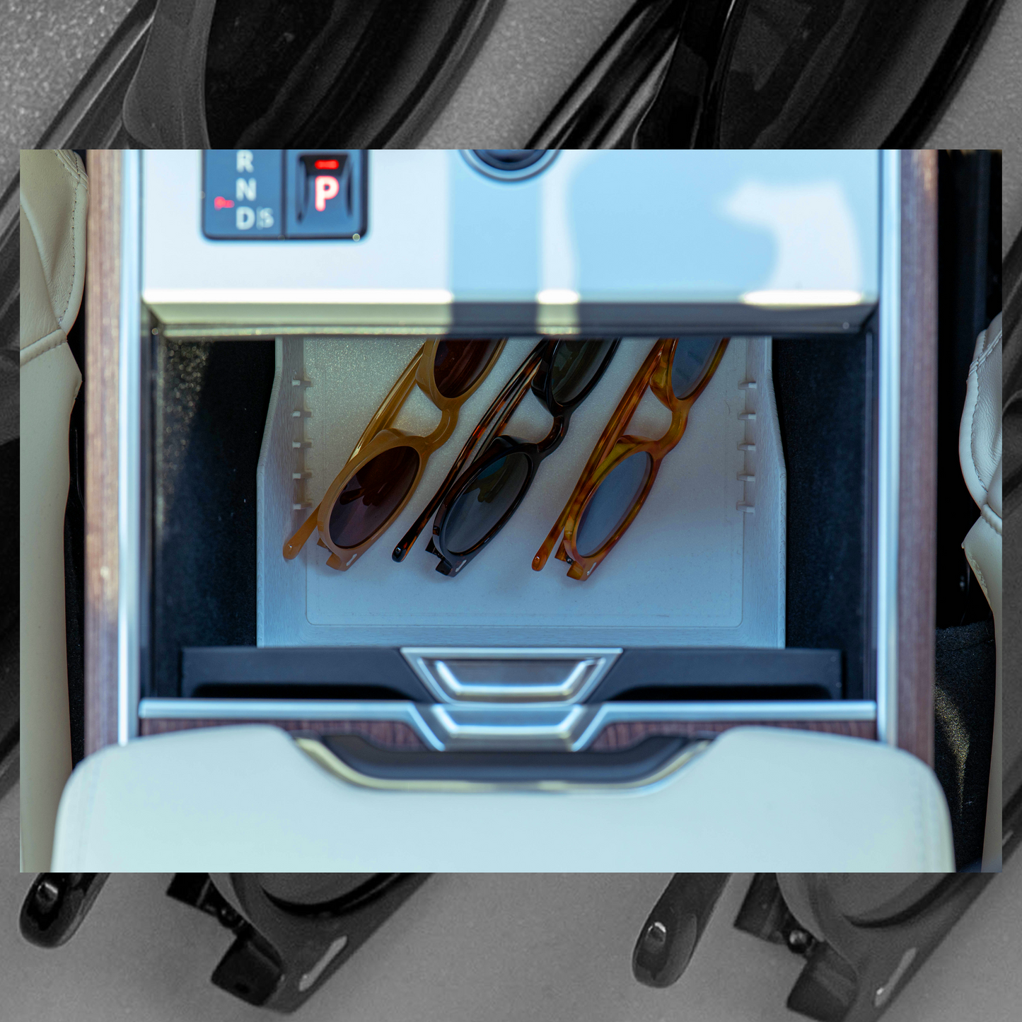 Sunglasses clearly visible inside the bright white tray through the partially open cupholders of Range Rover